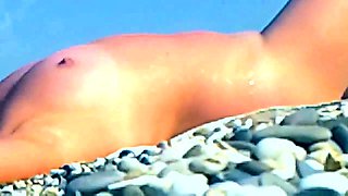 Nudist beach voyeur finds a sexy brunette enjoying the sun