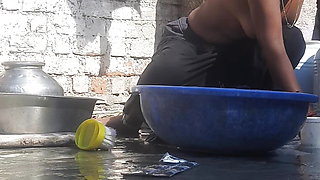 Indian stepsister is preparing to take a bath while washing clothes in the open courtyard of the house