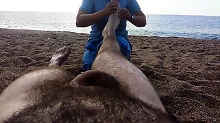 Lucky guy has a sexy lady massaging his feet on the beach
